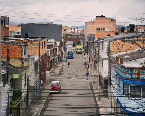 A person walking calmly down a tree-lined street in a Colombian neighborhood